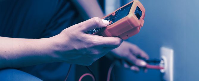 Hände Messen mit einem Messgeräte eine Steckdose in der Wand