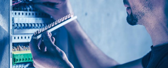 Mann setzt neue Elemente in einem Schaltschrank